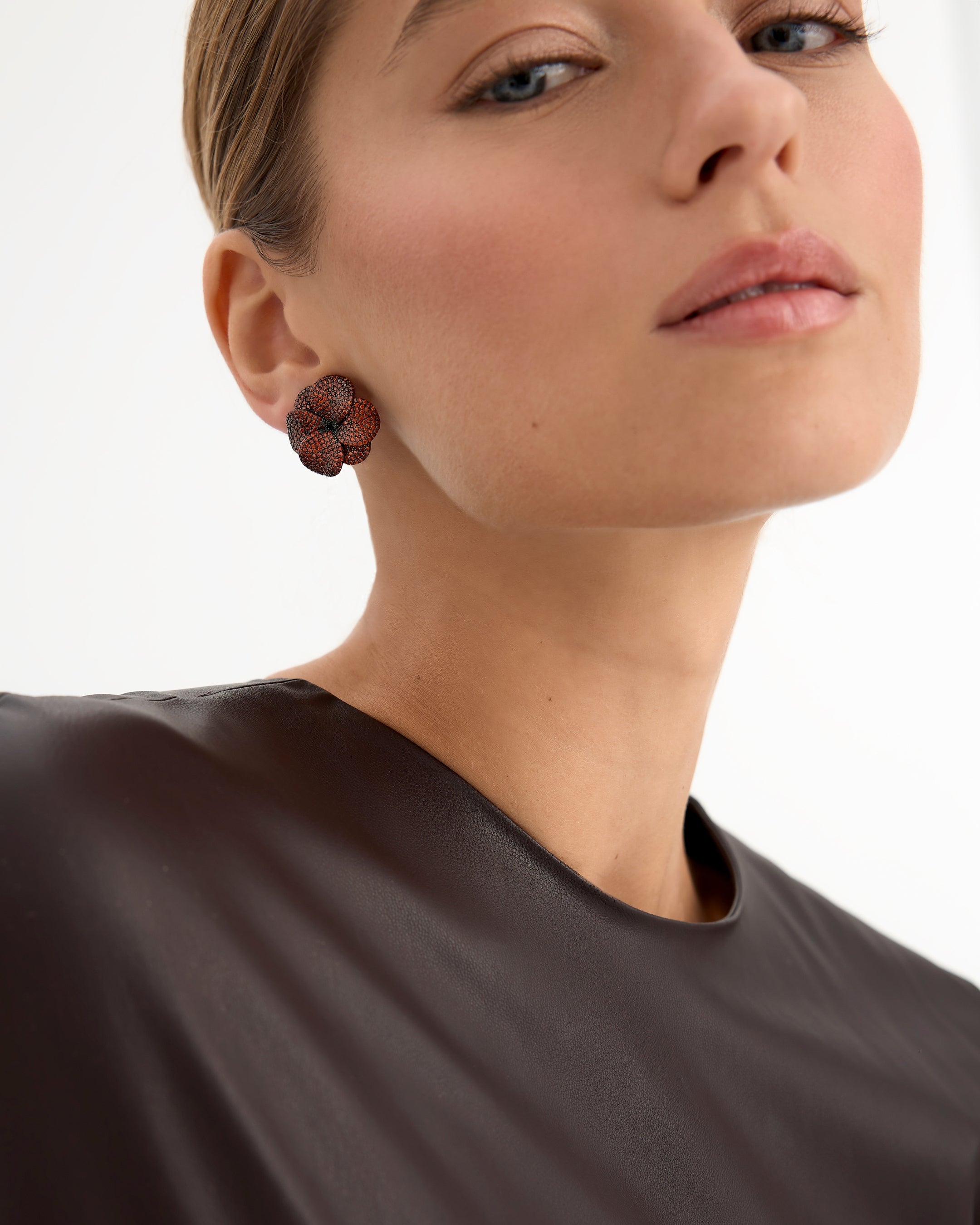 Los pendientes Roaring, inspirados en la vibrante energía de los 'Roaring Twenties', están fabricados en plata de ley 925 con un elegante baño de rodio negro. Su diseño en forma de flor, adornado con circonitas en tonalidad granate, aporta un estilo único y moderno. Con cierre de tuerca, estos pendientes son ideales para quienes buscan una pieza audaz y sofisticada que combine lujo con un toque diferente.