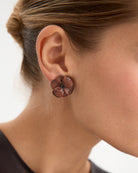 Los pendientes Roaring, inspirados en la vibrante energía de los 'Roaring Twenties', están fabricados en plata de ley 925 con un elegante baño de rodio negro. Su diseño en forma de flor, adornado con circonitas en tonalidad granate, aporta un estilo único y moderno. Con cierre de tuerca, estos pendientes son ideales para quienes buscan una pieza audaz y sofisticada que combine lujo con un toque diferente.